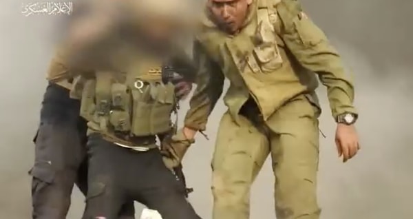Dikkatleri çeken ve tartışılan görüntüde Hamas tarafından esir alınan İsrailli asker, Hamas üyesinin kamuflajını birkaç kez elliyor.