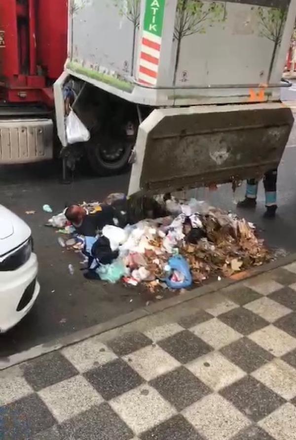 Belediye ekipleri, çöp dolu konteyneri vinçle kaldırdı.  Konteynerin alt kapaklarının yavaşça açılmasıyla çöplerle birlikte içindeki kişi yere düştü. Çöpten çıkan kişi ambulansla hastaneye götürüldü.