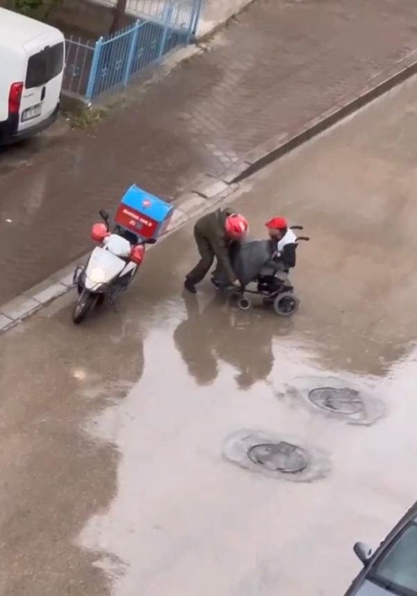 Yağmur etkisini sürdürürken yolda tekerlekli sandalye ile giden engelli vatandaşla karşılaşan motokurye kayıtsız kalmadı.