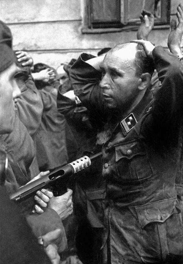 6. Varşova direnişçileri "PAST" binasının ele geçirilmesinden sonra esir alınan SS üyesini sorgularken. (Varşova, 20 Ağustos 1944. Fotoğraf: Eugeniusz "Brok" Lokajski.)