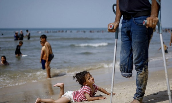 Bir çocuk, 24 Nisan 2024'te Gazze Şeridi'nin güneyindeki Rafah'ta çatışmaların devam ettiği sıcak bir günde etrafındakileri izliyor.